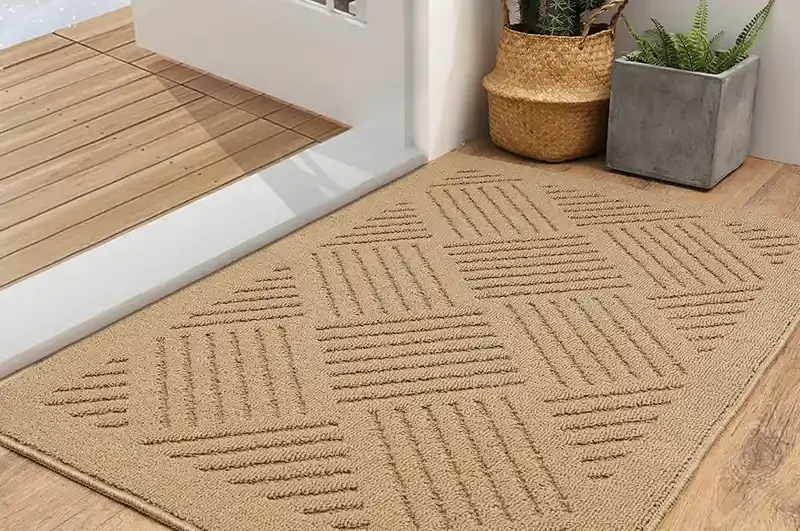 "سجادة باب عند مدخل المنزل تلتقط الغبار والرمال قبل دخول البيت، تظهر كيف تمنع الأتربة من الانتشار داخل الشقة."