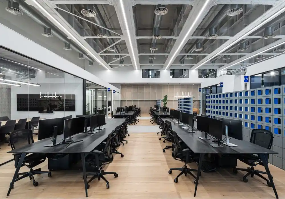 تصميم داخلي حديث لمساحة عمل مفتوحة في مبنى صناعي، تظهر نوافذ كبيرة وأرضيات نظيفة مناسبة لعمليات التنظيف المنتظمة.