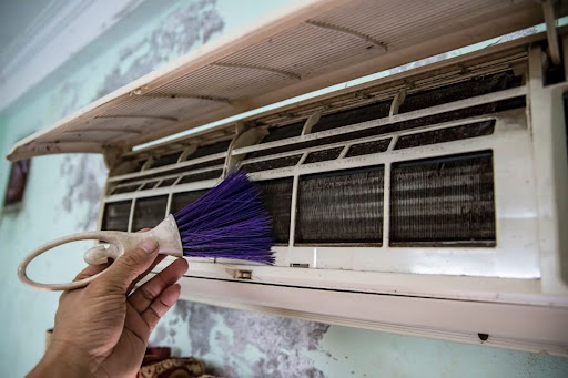 تنظيف لفائف المكيف الداخلية بدقة باستخدام فرشاة مخصصة لإزالة الغبار.