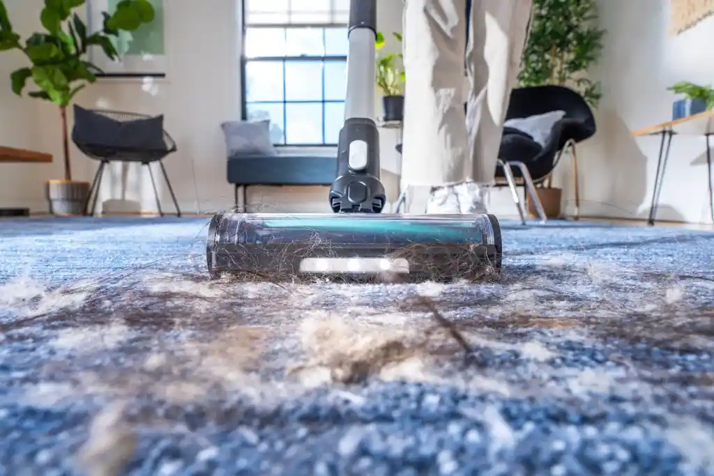 زوايا غرفة فيها طبقة غبار واضحة على الأرضية بالقرب من الأثاث، تعكس أماكن مهملة في التنظيف العادي.