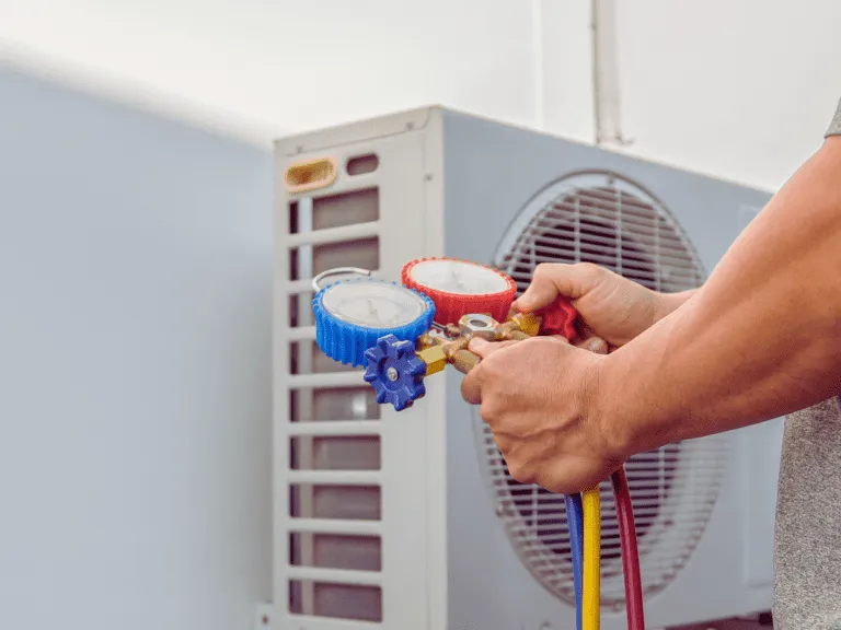 فني تكييف يستخدم مقاييس الضغط لفحص غاز الفريون وصيانة المكيف